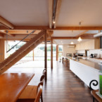 上部を吹き抜けとした風を感じる広いキッチン。サイド奥に4.9㎡のストックルーム、背面には6.4mのワークトップを備える L字型のLDKだが窓が開いていてデッキも部屋のようだ