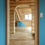 この家のアクセントカラーになっている空をイメージした青。階段下収納(一番奥)にも塗られている。 部屋から玄関、階段のあるLDKをみる