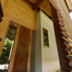 木製ルーバーと漆黒の丸太を抜けると木製の玄関ドアへ