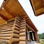 板張りの外壁にダイナミックなハンドカットログを組み合わせた サドルノッチの丸太組と軒の深い屋根